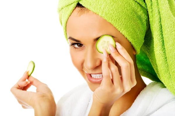 Woman in bathrobe applying cucumber on eyes — Stock Photo, Image