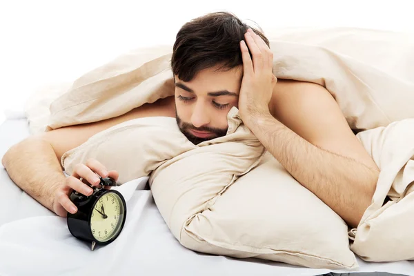 Uitgeput man wordt gewekt door een wekker. — Stockfoto