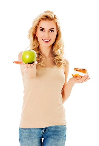 Mujer joven sosteniendo una manzana y una galleta — Foto de Stock