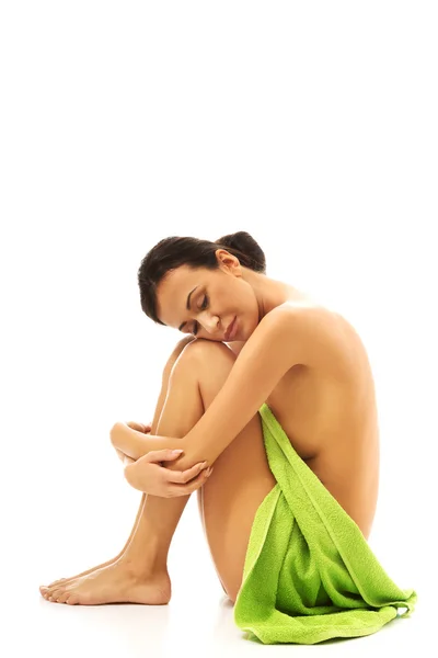 Kvinna sitter uppkrupen insvept i handduk — Stockfoto