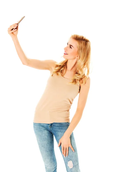 Happy young woman taking pictures of herself at smart phone — Stock Photo, Image