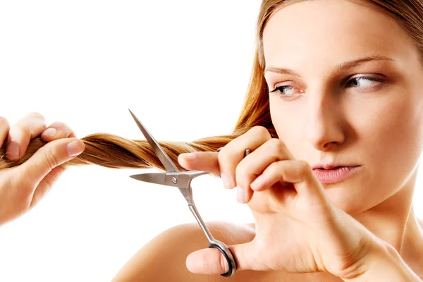 Jovem loira cortando seu cabelo com tesoura . — Fotografia de Stock