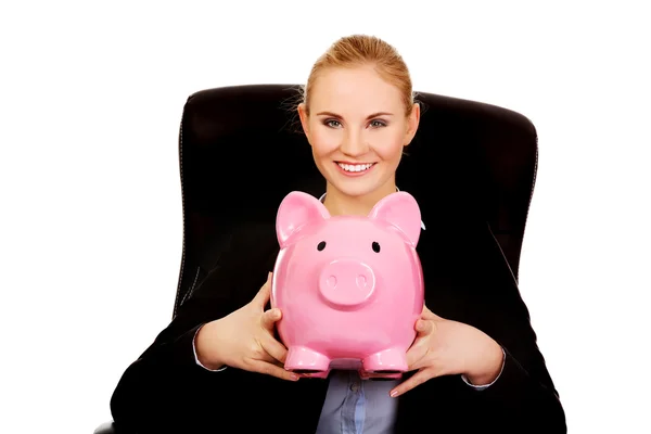 Business woman sitting on armchair and holding piggybank — Stock Photo, Image