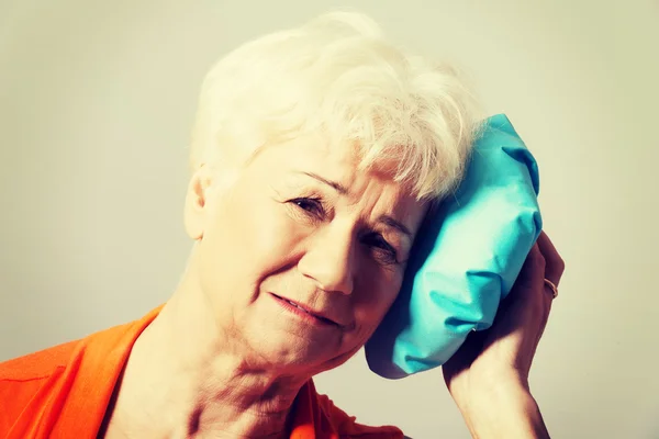 An old lady with ice bag by her head.