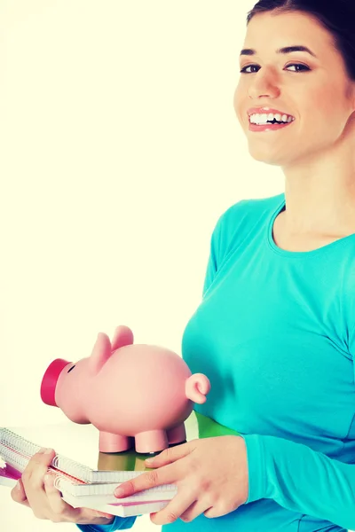Casual student woman holding workbook and piggy-bank. — Stock Photo, Image