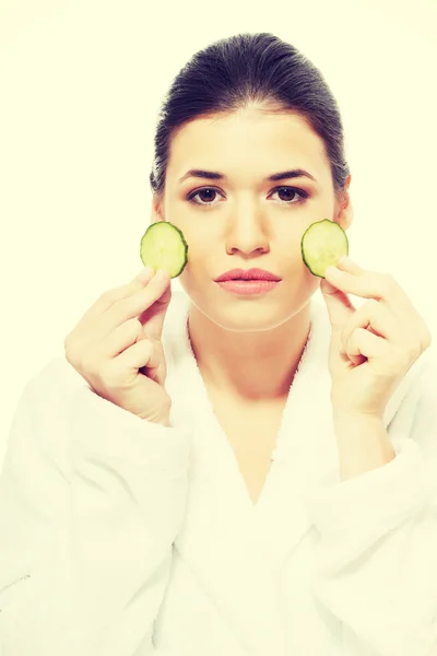 Mulher bonita em roupão segurando fatias de pepino . — Fotografia de Stock