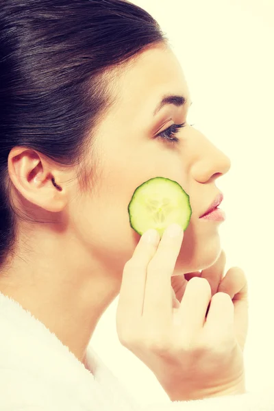 Hermosa mujer en albornoz sosteniendo rebanadas de pepino . — Foto de Stock