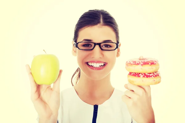 Doctora joven, enfermera sosteniendo una manzana y rosquillas . — Foto de Stock