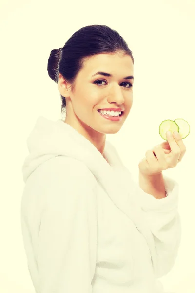 Beautiful woman in bathrobe holding cucumbers. — Stock Photo, Image