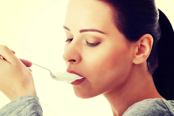 Junge Gelegenheitsfrau isst einen Joghurt. — Stockfoto