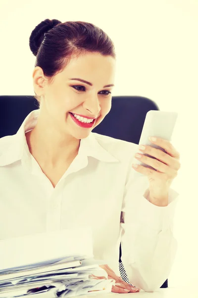 Hermosa mujer de negocios sentada junto a un escritorio con un montón de papeles . — Foto de Stock