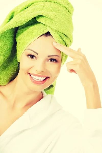 Beautiful woman in bathrobe and turban is touching her forehead. — Stock Photo, Image