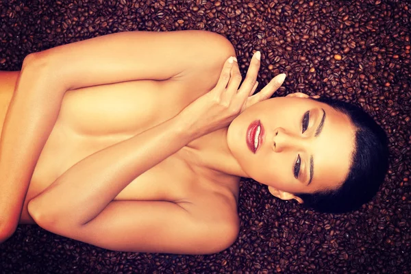 Linda mulher de topless deitado em grãos de café . — Fotografia de Stock
