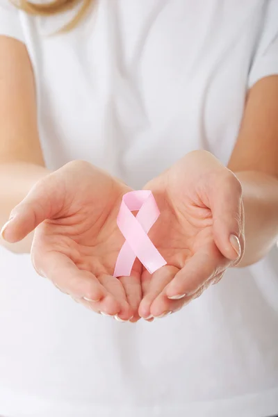 Manos sosteniendo cinta rosa de conciencia de cáncer de mama — Foto de Stock