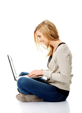 Gülümseyen kadın dizüstü bilgisayar kullanıyor.