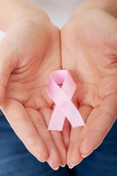 Manos sosteniendo cinta rosa de conciencia de cáncer de mama — Foto de Stock