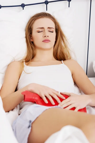 Close up de mulher com garrafa de água quente na cama — Fotografia de Stock