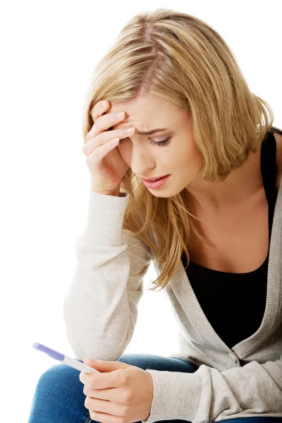 Sad young woman holding pregnancy test — Stock Photo, Image