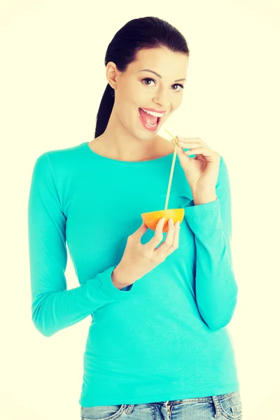 Woman drinking orange juice straight from fruit — Stock Photo, Image