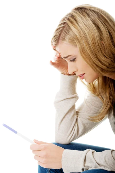 Sad young woman holding pregnancy test — Stock Photo, Image