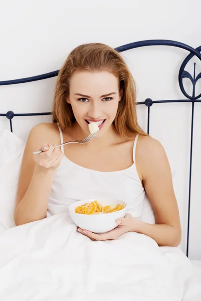 Vrouw eten ontbijt in bed — Stockfoto