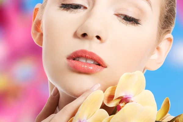 Hermosa mujer con una flor de orquídea — Foto de Stock