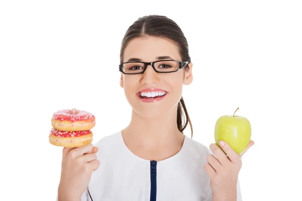 Nutricionista sosteniendo un pastel y manzana — Foto de Stock