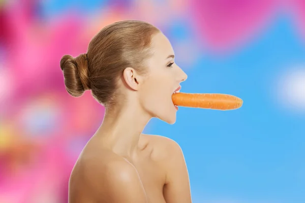 Kobieta z marchewki w usta — Zdjęcie stockowe