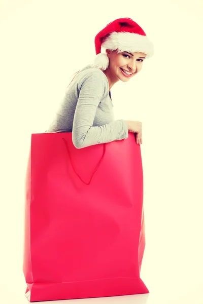 Beautiful girl wearing santa hat in red shopping bag. — Stock Photo, Image