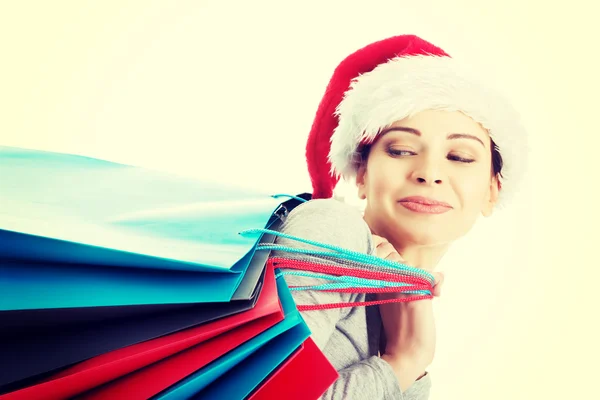 Hermosa mujer en santa hat llevando bolsas de compras . — Foto de Stock