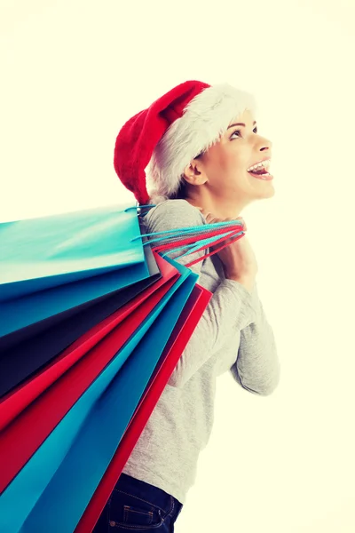 Hermosa mujer en santa hat llevando bolsas de compras . —  Fotos de Stock