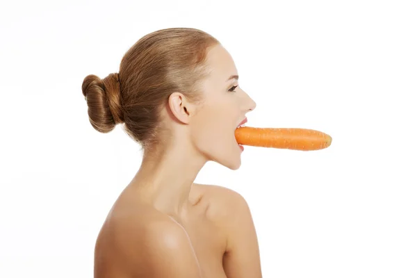 Portrait of nude woman eating a carrot — Stock Photo, Image