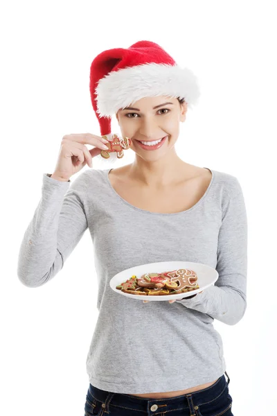 Happy woman in santa hat eating christmas cookies — Stock Photo, Image
