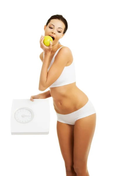 Счастливая стройная женщина с яблоком и весом — стоковое фото