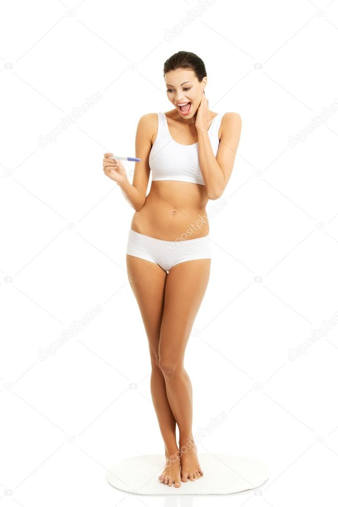 Full length happy woman holding pregnancy test