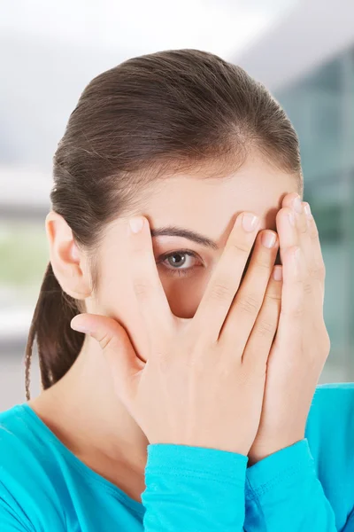 Shy teenage girl peeking through covered face — Stock fotografie