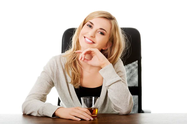 Happy woman sitting at the desk with cup of tea — Stock Photo, Image