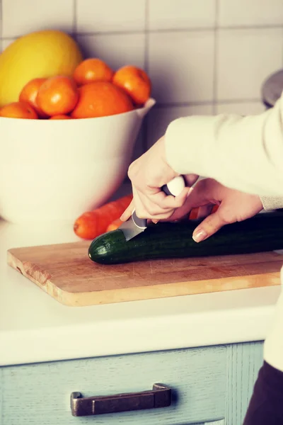 Caucásico atractivo joven mujer está cortando pepino . — Foto de Stock