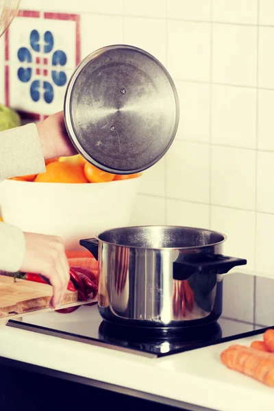 Vacker kaukasisk kvinna står i köket och matlagning. — Stockfoto