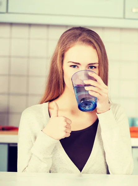 Mooie Kaukasische vrouw zitten in de keuken en drinken. — Stockfoto