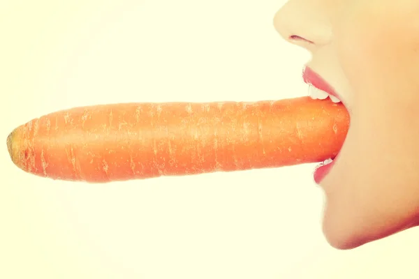 Beautiful profile of caucasian woman eating raw fresh carrot. Royalty Free Stock Photos