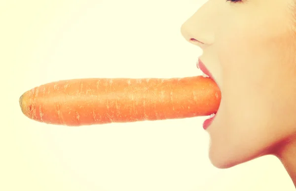 Beautiful profile of caucasian woman eating raw fresh carrot. Stock Image