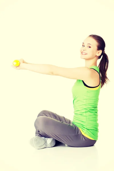 Attractive young woman sittinh and holding free weights. — Stock Photo, Image