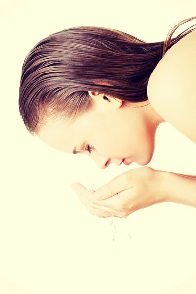 Mujer joven lavándose la cara con agua clara — Foto de Stock