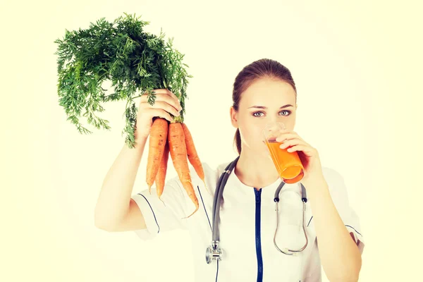 Female doctor holding healthy carrots. — Stock Photo, Image