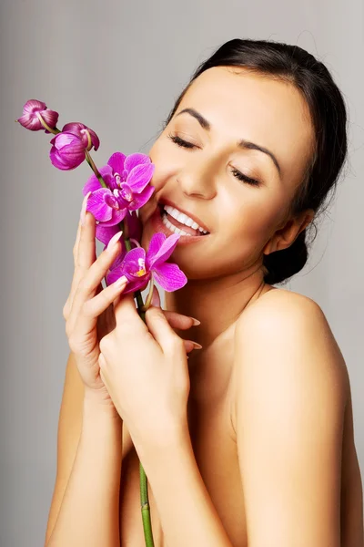 Donna nuda con orchidea viola e occhi chiusi — Foto Stock