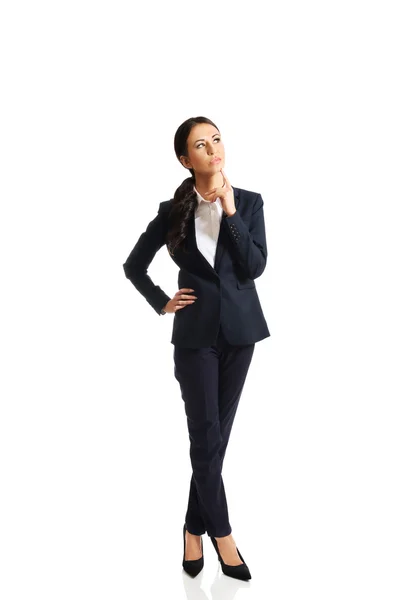 Full length thoughtful businesswoman with a finger under chin Royalty Free Stock Images