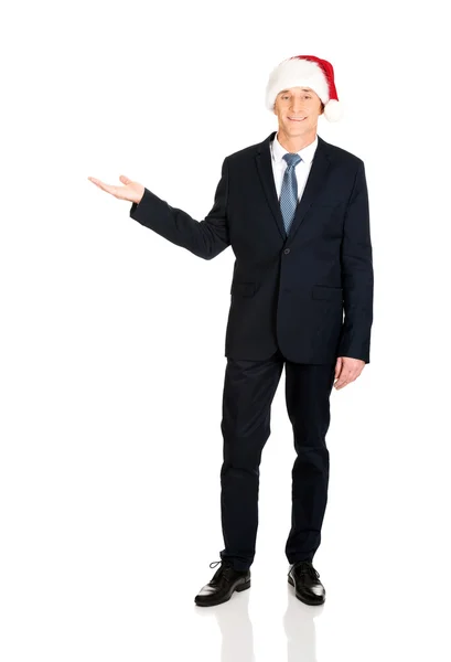 Businessman wearing santa hat with welcome gesture — Stock Photo, Image