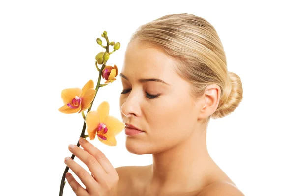 Schöne nackte Frau mit orangefarbenen Orchideenblüten — Stockfoto