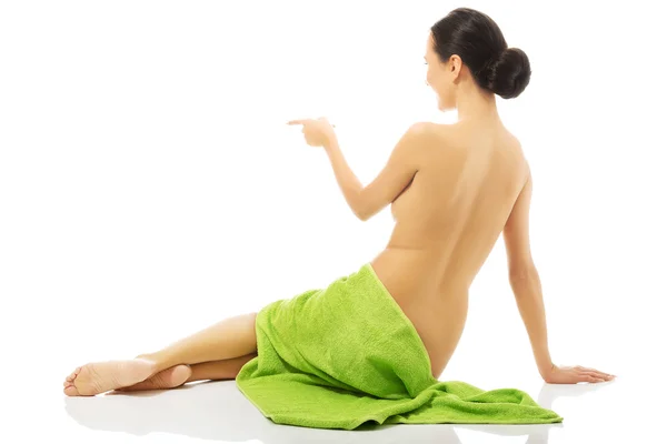 Вид сзади женщина завернутая в полотенце указывая влево — стоковое фото